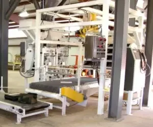 Industrial dual-spout bagging system with white steel frame, control panel, and mesh conveyor.
