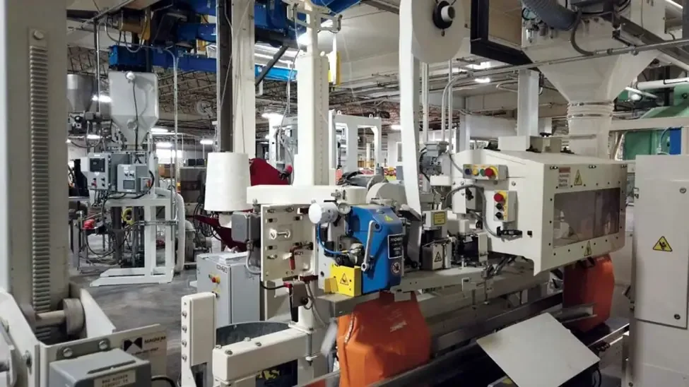 White Magnum bagging line filling orange bags beneath a roll of packaging film.