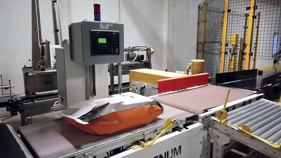 Filled orange bag on a Magnum conveyor beside a Data Scale weigh station reading 36.04.