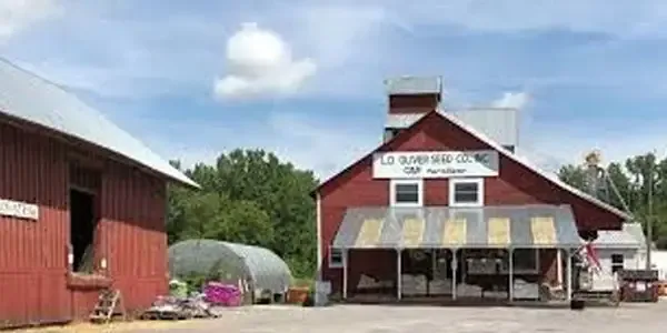 Red wooden L.D. Oliver Seed Co. building with white signage and a gravel lot in the foreground.